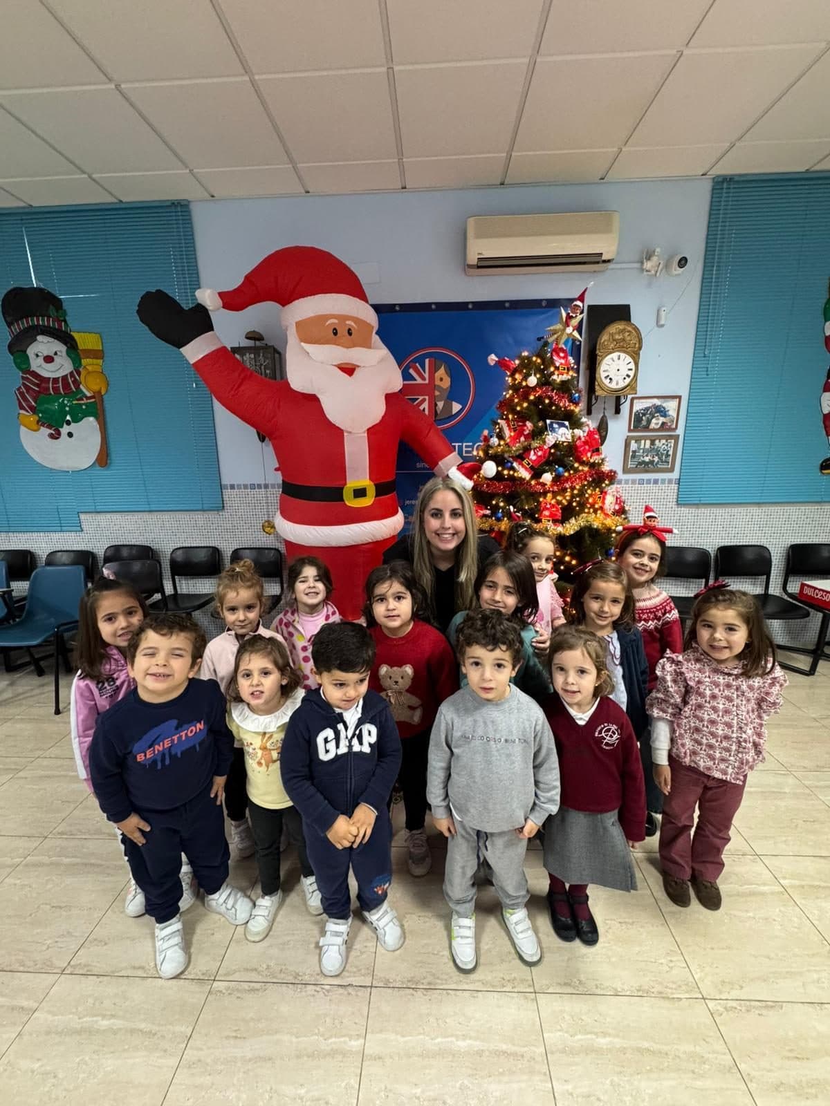 Los alumnos de Infantil con su profesora, delante del árbol de Navidad de la academia