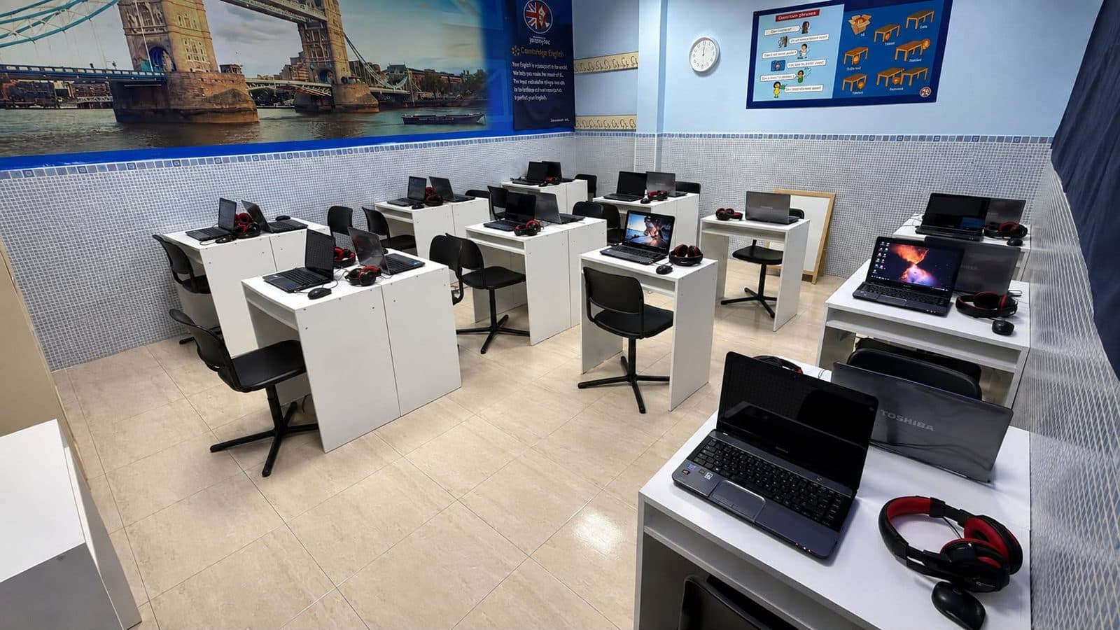 El aula de ordenadores de la academia, con un portátil y auriculares en cada mesa
